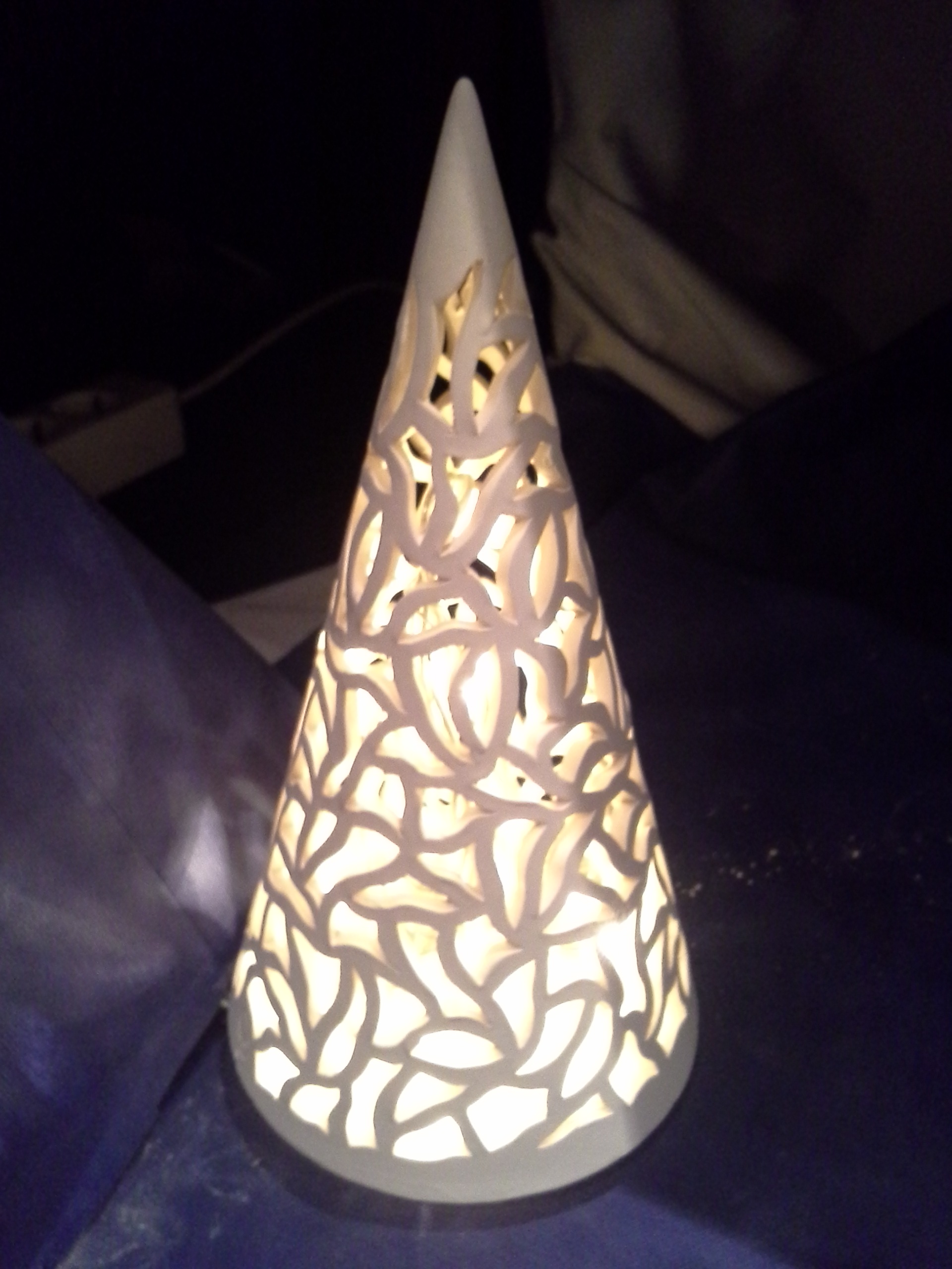 Ein beleuchteter Kegel aus geschnitztem Ton auf der Seite Ton schnitzen